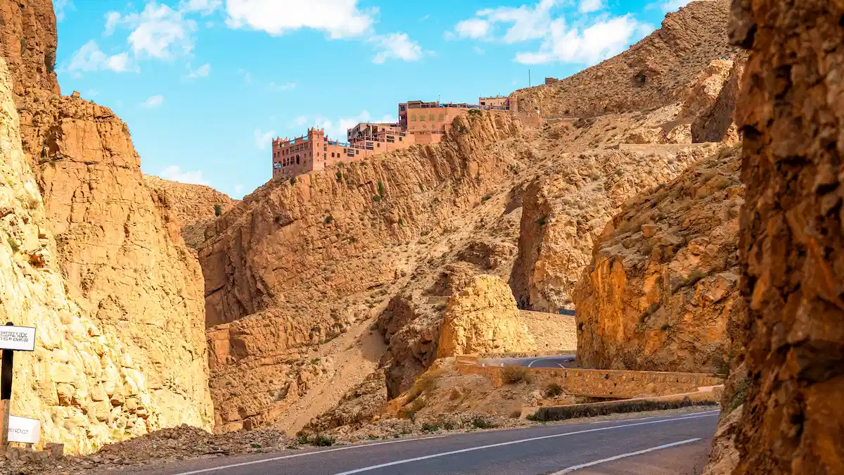 road in between the mountains with buildings on top nearby dades valley in morocco