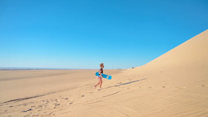 young man sandboarding in sahara desert of nerzouga in morocco