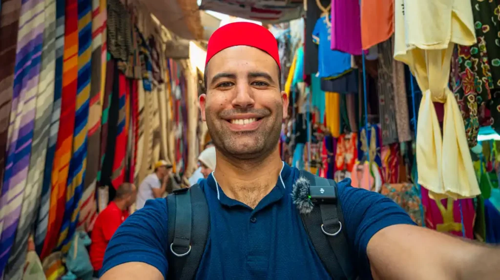 badr rachadi in the streets of Fez medina with background of carpets behind him during a morocco private tours