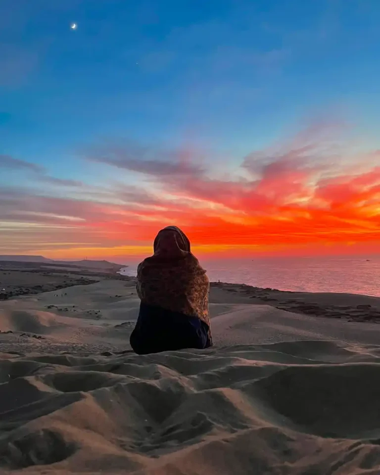 woman sitting in the sand during sunset in agadir