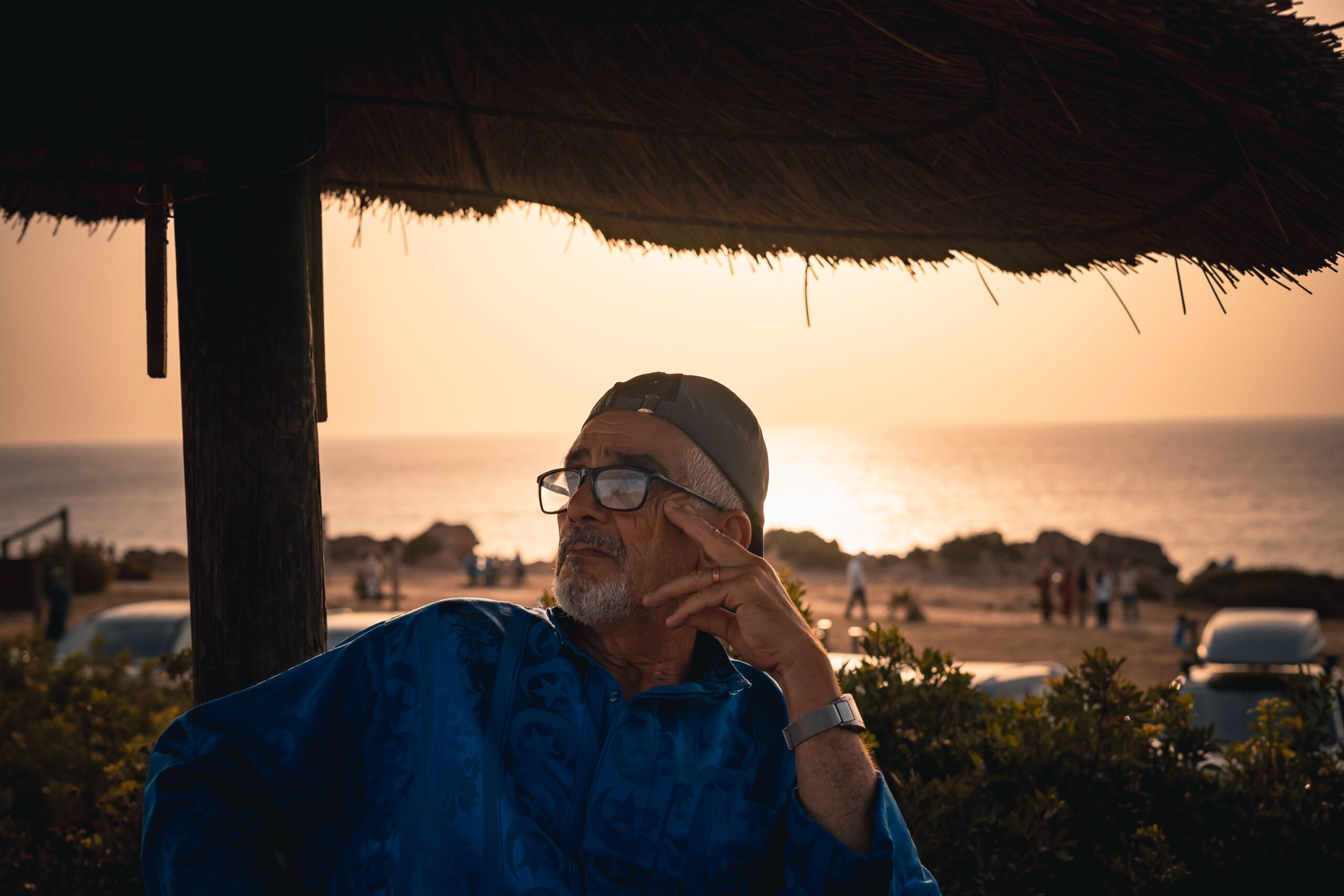 Man sitting under a beach umbrella at sunset in Casablanca; casablanca perfect beach day;